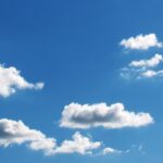 Peaceful blue sky filled with fluffy white clouds on a sunny day.